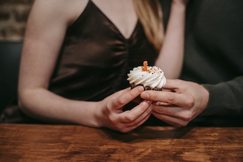 Anonymous couple celebrating with cupcake in cafe