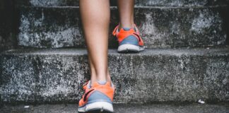 person wearing orange and gray Nike shoes walking on gray concrete stairs